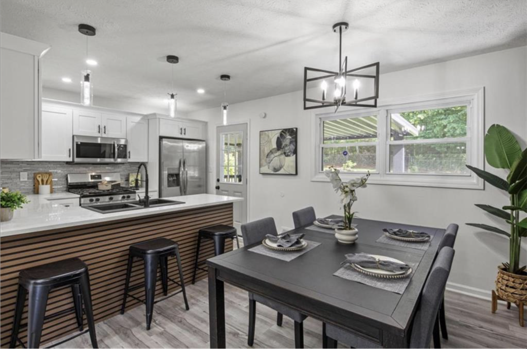 Staged dining room beside a kitchen with a wood slat island