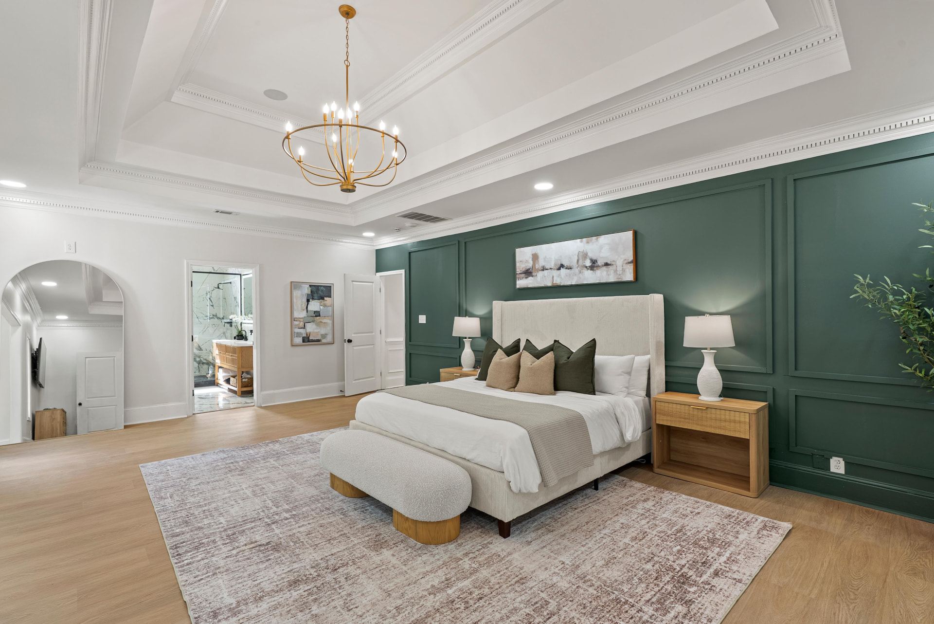 Staged primary bedroom with green paneled walls and chandelier
