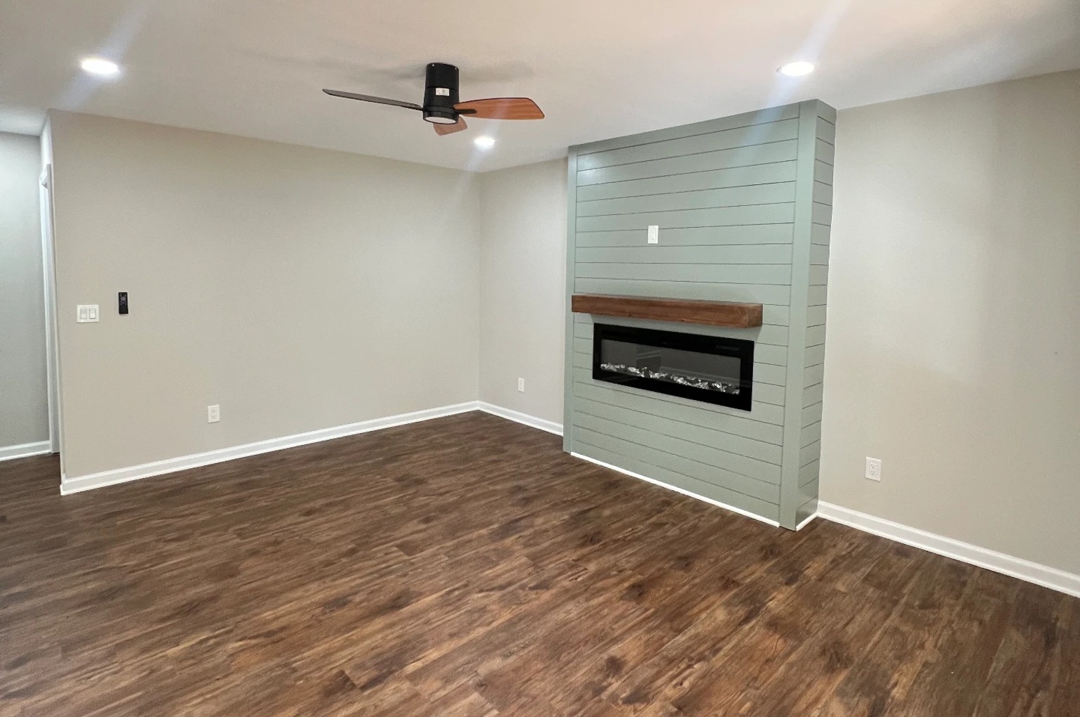 Empty living room with a sage shiplap fireplace before professional staging