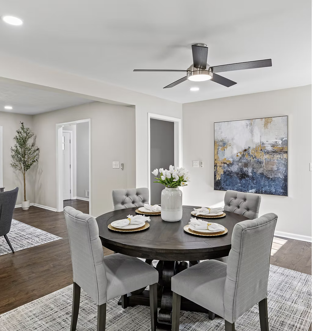 Staged dining room with a round table, gray chairs and abstract artwork